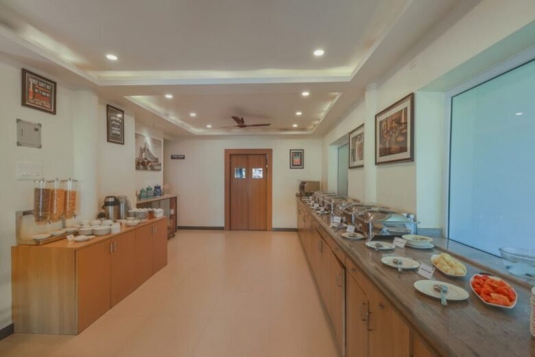 Salcete Beach Resort7 - Shrinath Adventures - Desert Camp Jaisalmer Hotel breakfast buffet in a bright dining area with a long counter of chafing dishes, fruit bowls, and cereal dispensers on the left.