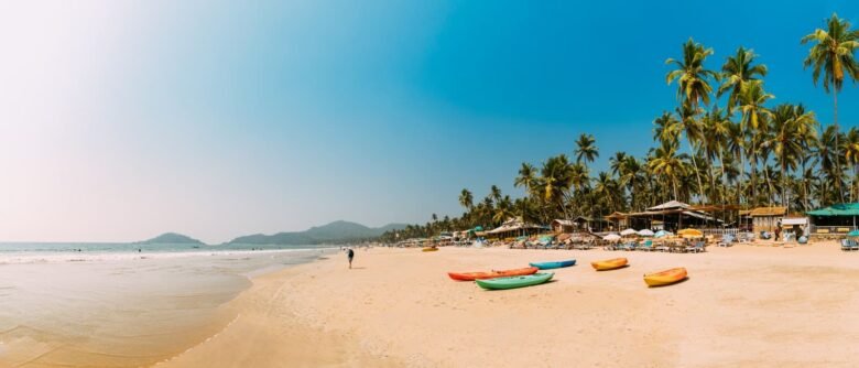 goa tour packages - Shrinath Adventures - Desert Camp Jaisalmer Sunny tropical beach with palm trees, colorful kayaks on golden sand, and beachside huts.