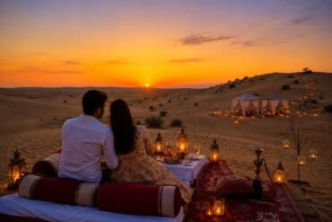 Couple seated on a desert rug at sunset, enjoying a candlelit dinner with lanterns and tents in the background